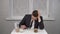 A sleepy young man in a suit eats cereal and drinks coffee. Young businessman at home in the morning kitchen.