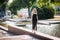 slender aged woman walks barefoot along a picturesque fountain in a city park