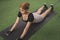 A slender asian woman does a sphinx stretch pose on a black mat. Warming up for a workout at the gym