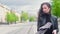 Slender attractive girl in a black leather jacket walks along the street of the city on a sunny summer day.