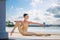 Slender ballerina in pointe shoes and tight-fitting suit posing against backdrop of the sea and sky with clouds