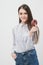 A slender beautiful brunette girl on a white background holding a pink glazed donut and a red apple.