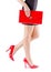 Slender beautiful womanish feet in red shoes and mini bag