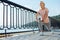 Slender elderly woman doing lunges on the bridge