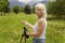 Slender elderly woman with gray hair with a compass in her hands for orienteering and sticks for walking