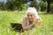 Slender elderly woman with gray hair lies on the grass and communicates via laptop