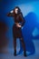 Slender fashion model in black clothes on a blue background.