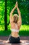 slender girl coach practices yoga in a summer park