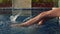 Slender girl sunbathes and dangles her legs in pool