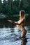 Slender girl teenager in swimsuit splashing water in pond
