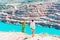 A slender girl in a white shirt walks alone by the sandy career. Against the background of mountains and a blue azure lake.