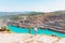 A slender girl in a white shirt walks alone by the sandy career. Against the background of mountains and a blue azure lake.