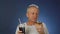 A slender middle-aged man eats a cake with pleasure and drinks a carbonated drink from a large glass with a straw.