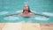 Slender model in the sky-blue bathing suit swims under water in a swimming pool in the back yard of private house, girl