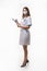 Slender nurse in medical dress and medical mask records data on white background