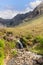 Slender waterfall feeding Fairy Pools with Isle of Skye\\\'s Cuillin mountains in the backdrop