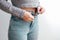 A slender woman fastens a button of her blue jeans. Weight ungain woman getting dressed wearing jeans. Close up of girl buttoning