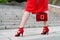 A slender woman in a red dress with a handbag climbs elegantly up the stairs, rear view