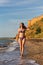 Slender woman in swimsuit walks in sea surf