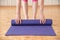 Slender woman unfolds purple mat for gymnastics or yoga in the gym