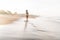 Slender woman walking on wet sandy seacoast