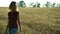 A slender woman walks on a wheat field and smiles on a Sunny summer day.