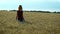 A slender woman walks on a wheat field and smiles on a Sunny summer day.