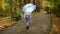 Slender woman in white leather jacket and jeans walking in the autumn Park with a blue umbrella in the rain