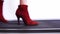 Slender women`s legs in red boots with thin heels walking on the catwalk presenting a new collection of shoes