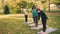 Slender young ladies are practising yoga outdoors in park under guidance of experienced teacher, woman is speaking and