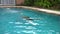 Slender young woman beautifully dives and swims under water in the pool, a great vacation in a private home patio, shot