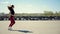 A slender young woman runs through the square against the backdrop of folded car wheels. Morning jogging of an active