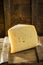 Slice of asolo cheese on wooden board on dark background