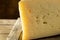 Slice of asolo cheese on wooden board on dark background