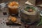 A slice of bread with poultry pate and orange gam, glass jar with poultry pate, decorated with almonds and rosemary, and jar with