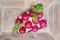 Slice of bread spread with cream cheese and topped with half radishes, wooden background