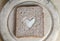 Slice of Brown Bread with White Heart on Vintage Bread Board