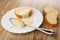 Slice of bun poured condensed milk, spoon in plate, pieces of bun on table