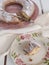 Slice of cake Ciambellone with crumbs on ceramic plate painted with floral motifs, cloth towel and mother of pearl fragments.