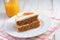 Slice of carrot cake  Pastel de zanahoria with icing and marzipan carrot on white background with carrot juice