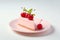 A slice of a cheesecake on a pink plate with glossy red cherries on top, against a clean white background