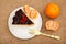 Slice of chocolate cake decorated with bunch of viburnum, fork and oranges