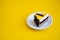 Slice of chocolate cake with orange jelly top on flat yellow background