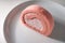 Slice of a delectable pink Swiss roll cake on a white plate