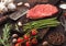 Slice of fresh raw barbeque braising beef steak on chopping board with asparagus and garlic with tomatoes and salt with pepper on