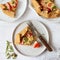 Slice of galette with tomatoes and cheese. Whole wheat rustic pie with tomatoes, cheeseand herbs. Square image