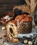 Slice of Glazed Easter cake or bread kulich on rustic wooden table with colored easter eggs in basket and spring flowers. Happy