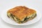 Slice of Greek Spanakopita Pie on a White Plate