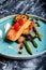 Slice of grilled salmon garnished with cooked green asparagus, sauted cherry tomatoes and lemon