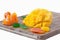 Slice half the mango with Mandarin orange , candied kumquat and other fruits lying on a wooden Board isolated on white background